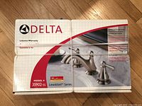 Box showing full product image of Delta Lewiston Series chrome bathroom faucet with lifetime warranty, model number 35902-SS.