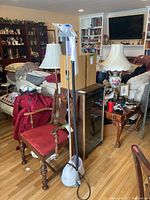 Full view of the garment steamer set up in a living room environment showing the base, pole, and steam head.