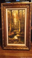 Full view of framed oil painting showing the wooded landscape and ornate frame.