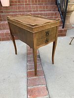 Side view of vintage wooden end table showing scalloped top edges and metal ring pull handles on two drawers.
