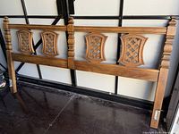Full view of the vintage solid wood queen size headboard showing four carved decorative panels and turned posts.
