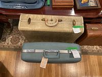 Top view of two vintage suitcases: one light beige Samsonite and one seafoam green Oshkosh, showing size and color