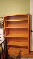 Front view of the wood bookcase showing five shelves and natural wood finish