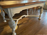 Side view showing solid oak top with decorative inlay and turned legs painted white.