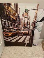 Photo of the New York City street scene canvas poster with yellow taxis on a pedestrian zebra crossing, stretched on a wood frame, leaning against wall.