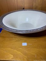 Top angled view showing the interior cream enamel with reflective surface and detailed floral engraved border around the platinum-looking metal rim