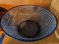 Top-down view of the decorative bowl showing the black wire framework and blue glass beads woven throughout the bowl.