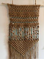 Full view of the natural rope macrame wall hanging with visible copper beads and wooden dowel.
