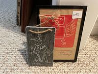 Soapstone etching in front of framed print on carpet