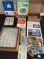 View of entire stamp collection including Canadian Centennial Set, Oak Frame of Canadian stamps, Worldwide Album, Stamp Finder book, and box of loose stamps.