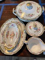 Top view of four Noritake Tremont serving pieces showing floral designs, gold trim, and lids on lidded pieces.