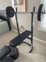 Full view of the new weight bench with barbell rack and weights loaded on the barbell.