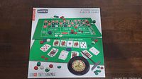 Front of box showing images of four casino games including blackjack, roulette, craps, and poker game mats with chips and cards