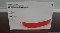 Box of Sharper Image 10 inch Ceramic Oval Baker showing brand, product name, and features in white box with image of oval baker in red and white.