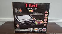 Front view of the boxed T-fal OptiGrill showing branding, product image and key features.