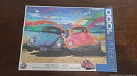 Puzzle box front photo showing artwork of two VW Beetle cars with colorful heart-themed sky and title 'VW Beetle Love'.