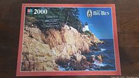 Puzzle box showing the scenic coastal image with lighthouse and rocky cliffs, indicating 2000 pieces.