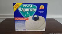 Boxed Vicks Vaporizer showing the front of the retail packaging with product image and features.