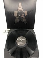 Front view of vinyl record partially out of die cut star-shaped gatefold sleeve, showing label on Side 1 with Bowie album artwork.