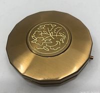 Close up photo of the gilt gold tone Yardley round vanity case with floral design on top.