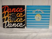 Two 12-inch vinyl records in sleeves, one with 'Dance Dance Dance' design and one blue striped 'Sunnyview' sleeve.
