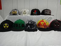 View of nine different adjustable baseball caps arranged in two rows on a white cloth background.