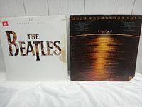 Front covers of both vinyl albums: The Beatles '20 Greatest Hits' with white cover and Creedence Clearwater Revival greatest hits album with dark cover showing water reflection.