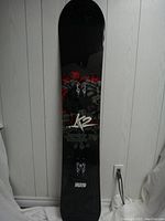 Full view of snowboard top side with black color and floral design and K2 logo.