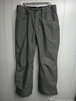 Front view of gray snowboard pants hanging showing the style, pockets and zipper placement.