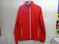 Full front view of the red Sunice jacket with white zipper and two zippered front pockets.
