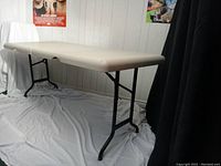 Portable table shown folded closed in half, approx. 36" length with folded legs under plastic top.