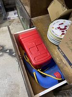 Image of a red and blue baby hanging swing with yellow rope stored in an open drawer in a basement or storage area