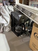 Photo of a black and silver CUISINE double-sided drip coffee maker with a glass pot.