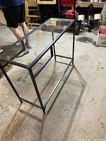 Side view of small metal and glass side table showing frame and lower glass shelf