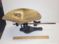 Full view of the antique commercial scale showing the large brass-colored weighing pan and black cast iron base with gold lettering and decorative bird weight.