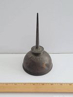 Side view of antique metal oil can with embossed "EAGLE" and metal spout, showing age and wear.