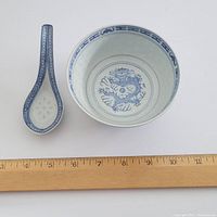 Blue and white ceramic bowl and spoon placed next to a ruler for size reference showing approximately 4 inches in diameter for the bowl.