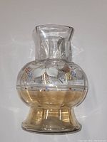 Clear glass pitcher with a square mouth and hand painted floral details on the rounded body showing two-tone coloration including clear and amber tint.
