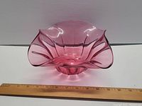 Front angle view of vintage cranberry glass flower bowl showing ruffled edges and fluted design.
