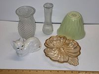 Photo of a white ceramic cat figurine, two clear glass vases with different textures, a light green glass bowl, and a peach-colored divided glass dish.