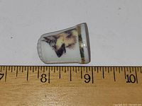 Side view of the German Shepherd image on white ceramic thimble with measuring tape showing size about 1.25 inches