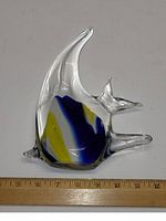 Side view of hand blown glass angelfish with blue and yellow color accents and clear glass fins, placed next to a ruler measuring approximately 8 inches tall.