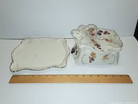 Porcelain lid and base of the cheese dish separated for scale on ruler showing 8 inch length.