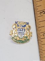 Close-up image of the vintage Coquitlam BC Canada lapel pin next to a ruler showing measurement for scale.