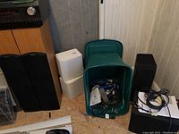 Overview showing Paradigm speakers, white boxes, green bin of cables, black subwoofer, and Integra unit atop cabinet