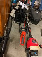 Full view of the Troy-Bilt trimmer, Black & Decker electric hedge trimmer, and Echo backpack blower on concrete floor