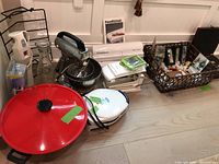 Overview of kitchen appliances and barware including Hamilton Beach stand mixer, FoodSaver vacuum sealer, red wok, barware basket