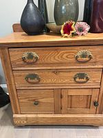 Front view of oak night chest showing two small top drawers, one large drawer below, cupboard door at bottom with brass Eastlake style handles.