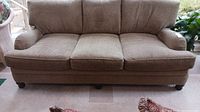 Full front view of beige tweed sofa showing six cushions and two accent pillows.