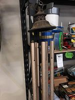 Full view of long metal wind chimes hanging showing decorative top and tubes